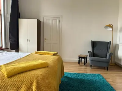 a bedroom with a bed with a yellow blanket and a chair at VS-Entire Flat-Central Scotland-Falkirk, Self-Check-in , Pet-friendly with Parking in Falkirk