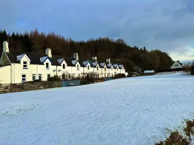 a snow covered field with a row of houses at Cosy Cottage with Woodburner by Crinan Canal Pets Welcome in Cairnbaan