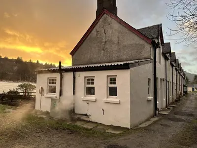 an old white house with smoke coming out of it at Cosy Cottage with Woodburner by Crinan Canal Pets Welcome in Cairnbaan