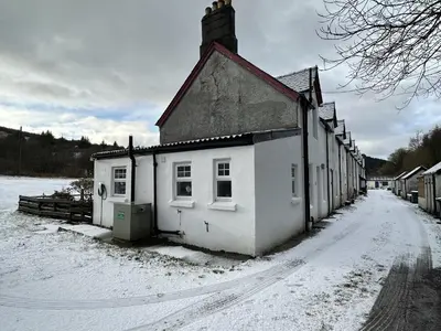 a small white building on a snow covered street at Cosy Cottage with Woodburner by Crinan Canal Pets Welcome in Cairnbaan
