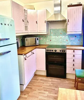 a kitchen with white cabinets and a stove top oven at Cosy Cottage with Woodburner by Crinan Canal Pets Welcome in Cairnbaan