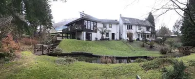 a large house with a pond in front of it at The River Inn in Killin