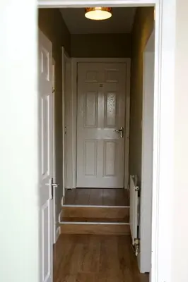 an empty hallway with a white door and stairs at 20min train to Edinburgh, The Coorie Inn in Inverkeithing