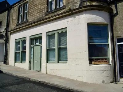 a building with green doors and windows on a street at 20min train to Edinburgh, The Coorie Inn in Inverkeithing
