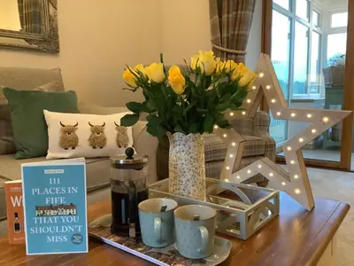 a table with a vase of yellow flowers and lights at 2 Bed in Rosyth oc-r30512 in Rosyth