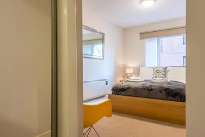 a bedroom with a bed with a mirror and a window at The Maltings in Edinburgh