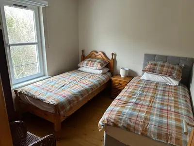 a bedroom with two beds next to a window at Church Bay House Rathlin in Rathlin Island