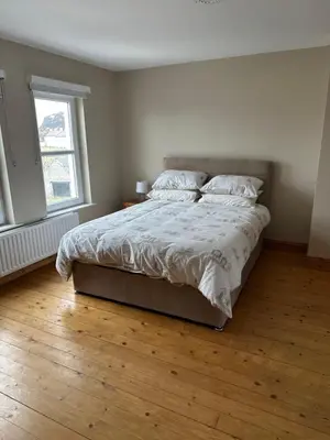 a bedroom with a large bed with a wooden floor at Church Bay House Rathlin in Rathlin Island