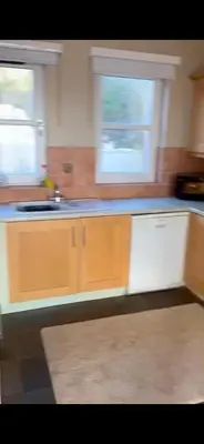 a kitchen with wooden cabinets and two windows in it at Church Bay House in Rathlin Island