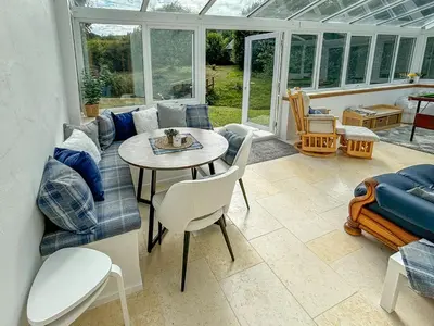 a conservatory with a couch and a table and chairs at Heatherdale in Dunoon