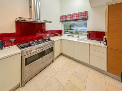a kitchen with white cabinets and a stove top oven at Heatherdale in Dunoon