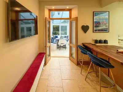 a kitchen with a bar and two blue chairs at Heatherdale in Dunoon