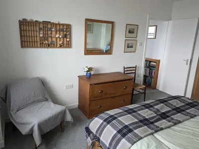 a bedroom with a bed and a chair and a mirror at Tigh Grianach in Port Charlotte