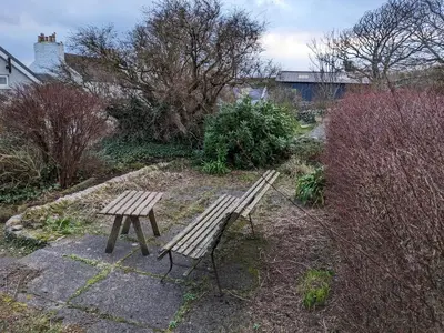 a wooden bench in a garden with trees and bushes at Tigh Grianach in Port Charlotte