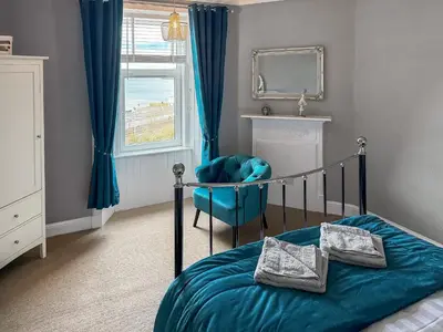 a bedroom with a bed and a chair and a mirror at Littlebay Apartment in Oban