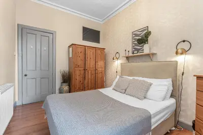 a bedroom with a bed and a wooden cabinet at Central, Cozy 2BR-1BA-Haymarket - with Parking in Edinburgh
