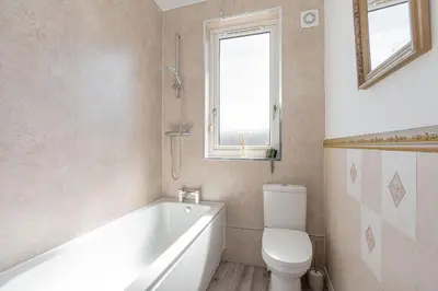 a bathroom with a tub and a toilet and a window at Spacious 3 bed flat- Free parking Edinburgh & Fife in Inverkeithing