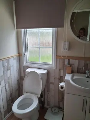 a bathroom with a toilet and a sink and a window at St Nicholas Number 5 in Turnberry