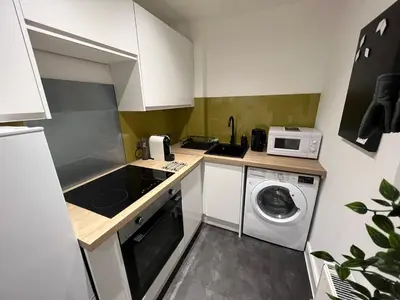 a small kitchen with a washing machine and a microwave at Stunning refurbished main door Marchmont apartment in Edinburgh