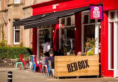 a red box restaurant with people sitting outside of it at Stunning refurbished main door Marchmont apartment in Edinburgh