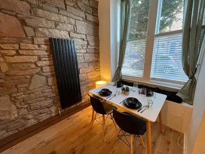 a table and chairs in a room with a stone wall at Stunning refurbished main door Marchmont apartment in Edinburgh