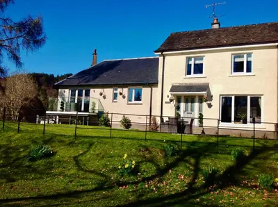 a white house with a fence in front of it at Lovely Riverside Holiday Home in Callander