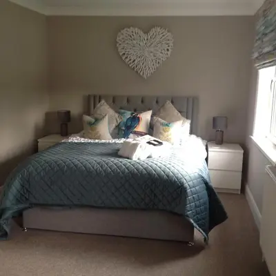 a bedroom with a bed with a heart on the wall at Lovely Riverside Holiday Home in Callander