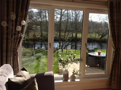 a room with a window with a view of a garden at Lovely Riverside Holiday Home in Callander