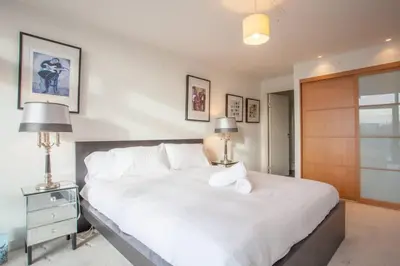 a bedroom with a large white bed and two lamps at Apartment with river view next to hydro in Glasgow