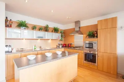 a kitchen with wooden cabinets and a counter top at Apartment with river view next to hydro in Glasgow