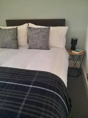 a bedroom with a large bed with pillows and a table at Doune 3 Outlander Apartment 1st floor in Stirling