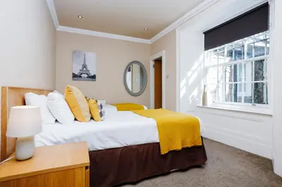 a bedroom with a bed with a yellow blanket on it at Large Central 3 Bed 3 Bath Apartment - New Town in Edinburgh