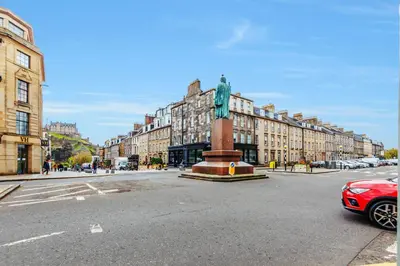 a statue in the middle of a street with buildings at Large Central 3 Bed 3 Bath Apartment - New Town in Edinburgh