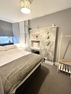 a bedroom with a large bed and a chair at Small Cosy Flat in Helensburgh