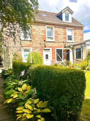 a house with a hedge and flowers in front of it at Small Cosy Flat in Helensburgh