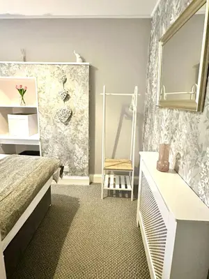 a bedroom with a bed and a mirror and a chair at Small Cosy Flat in Helensburgh