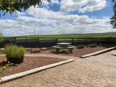 a picnic table in a garden with a fence at Marshill Farmhouse in Blackwood