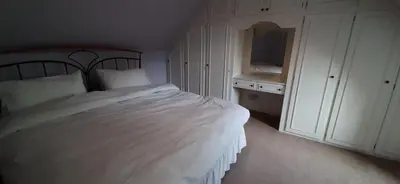 a bedroom with a white bed and a white cabinet at Marshill Farmhouse in Blackwood