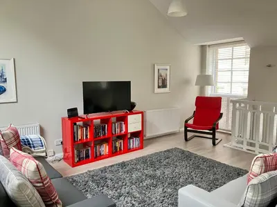 a living room with a red entertainment center with a flat screen tv at Park Mews Glasgow in Glasgow