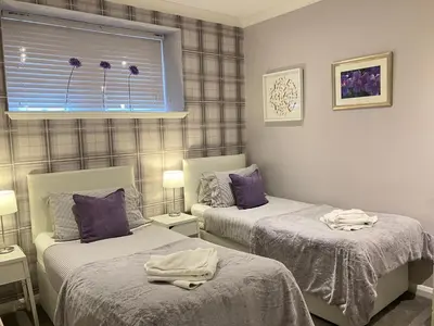 a bedroom with two beds with purple pillows and a window at Park Mews Glasgow in Glasgow