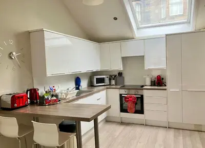 a kitchen with white cabinets and a wooden table at Park Mews Glasgow in Glasgow