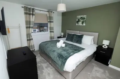 a bedroom with a large bed with two night stands at Pristine 3 bedroom house in East Kilbride
