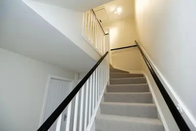 a winding staircase in a house with white walls and carpet at Pristine 3 bedroom house in East Kilbride