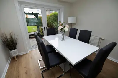 a white table with black chairs and a vase of flowers at Pristine 3 bedroom house in East Kilbride