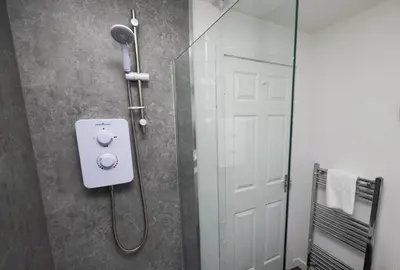 a shower with a shower head and a glass door at Pristine 3 bedroom house in East Kilbride