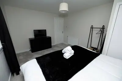 a bedroom with a black and white bed and a television at Pristine 3 bedroom house in East Kilbride