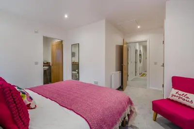 a bedroom with a pink bed and a red chair at 3 Bed in Fearnan oc-s29984 in Chesthill