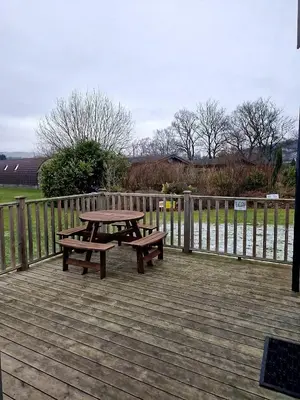 a picnic table and benches on a wooden deck at The Ness, Lodge with Hot Tub in Crieff