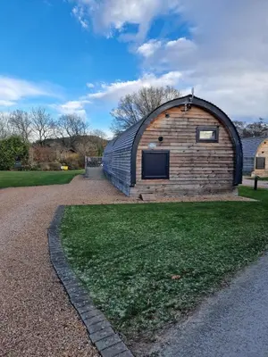 a large wooden building with a roof on the grass at The Ness, Lodge with Hot Tub in Crieff
