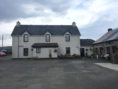 a white house with a black roof at Farmhouse in Clydebank